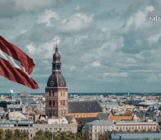 რიგა: ბალტიისპირეთის ჩრდილოური ელეგანტურობა – სრული გზამკვლევი ბიუჯეტური დასვენებისთვის ლატვიის დროშა და რიგის ხედი, რიგის ტაძრის (Dom) კოშკი